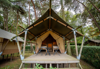 Un Duo Lodge en Familiepark Goolderheide, Bélgica, entre árboles, con terraza de madera y sillas de camping.