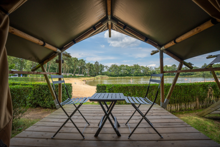 Blick aus der Duo Lodge im Familiepark Goolderheide, Belgien, mit Terrasse, See und Natur im Hintergrund.