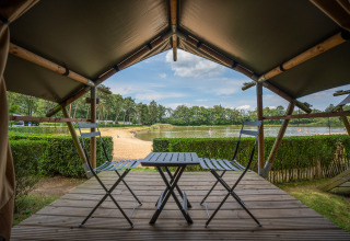 View from Duo Lodge at Familiepark Goolderheide, Belgium, with terrace seating and scenic lake in background.