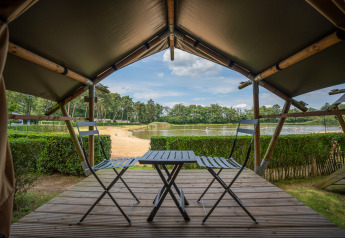 Vista desde Duo Lodge en Familiepark Goolderheide, Bélgica, con terraza, sillas y lago al fondo.