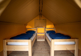 Vista interior de Duo Lodge con dos camas individuales y suelo de madera en Familiepark Goolderheide, Bélgica.