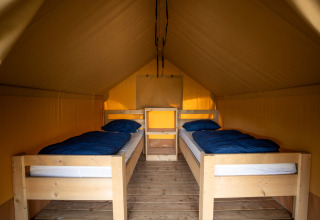Vista interior de Duo Lodge con dos camas individuales y suelo de madera en Familiepark Goolderheide, Bélgica.