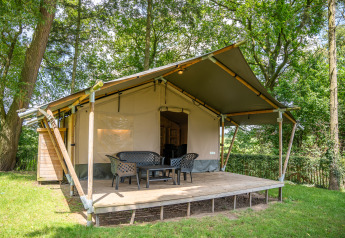 Safari tent Lake with a wooden deck and outdoor chairs, nestled among trees, ideal for a glamping stay.