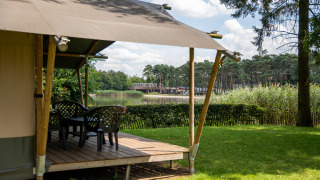 Tente safari avec terrasse au bord d’un lac à Familiepark Goolderheide, Belgique, vue sur la nature.
