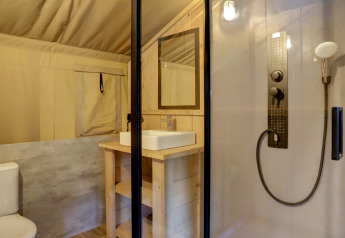 Safari-Zelt-Badezimmer mit moderner Dusche, Toilette und Waschbecken im Familiepark Goolderheide, Belgien.