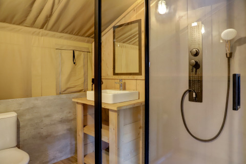 Safari tent bathroom with modern shower, toilet, and sink at Familiepark Goolderheide in Belgium.