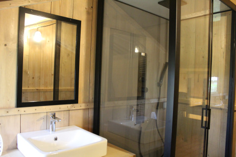 Bagno in tenda safari a Familiepark Goolderheide, Belgio, con lavandino, specchio e cabina doccia.