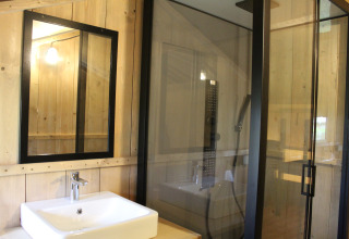 Bagno in tenda safari a Familiepark Goolderheide, Belgio, con lavandino, specchio e cabina doccia.