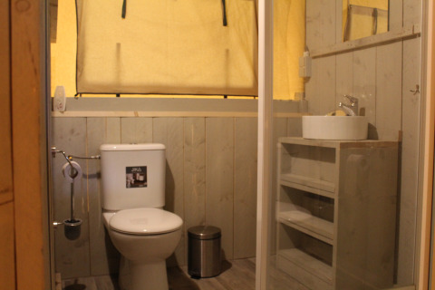 Badkamer in safaritent met toilet, wastafel en spiegel bij Familiepark Goolderheide, België.