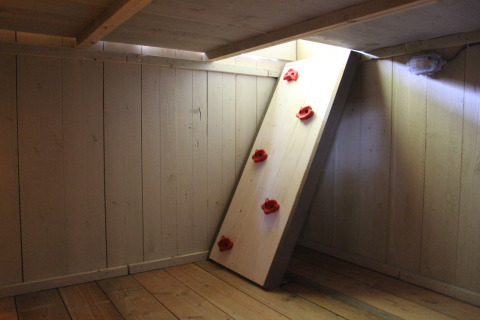 Interieur van een safaritent met houten vloer, wanden en een kleine klimwand bij Familiepark Goolderheide.