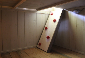 Interior of a safari tent with wooden walls and a small climbing wall with red holds at Familiepark Goolderheide.