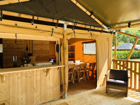 Tienda safari con instalaciones sanitarias privadas y muebles de madera en Familiepark Goolderheide, Bélgica.