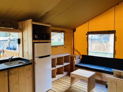Intérieur d’une tente safari avec sanitaires à Familiepark Goolderheide, Belgique, avec mobilier en bois.