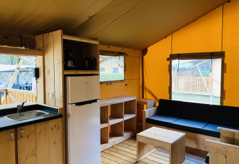 Intérieur d’une tente safari avec sanitaires à Familiepark Goolderheide, Belgique, avec mobilier en bois.