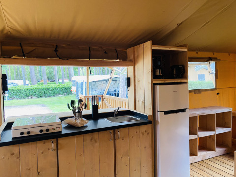 Area cucina in una tenda safari con fornello, lavello e frigorifero al Familiepark Goolderheide in Belgio.