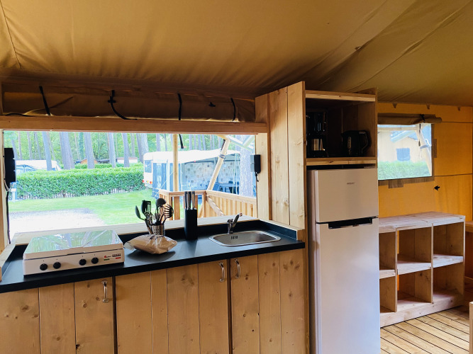 Área de cocina en una tienda safari con estufa, fregadero y nevera en Familiepark Goolderheide, Bélgica.