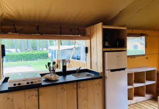Espace cuisine d’une tente safari avec cuisinière, évier et réfrigérateur au Familiepark Goolderheide en Belgique.