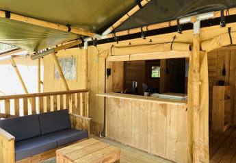 Tenda safari con servizi igienici al Familiepark Goolderheide in Belgio, con divano e tavolo in legno.