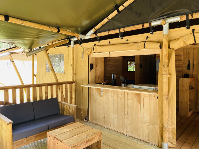 Safari-Zelt mit Sanitäranlagen im Familiepark Goolderheide in Belgien, mit Holzsofa und Bartresen.