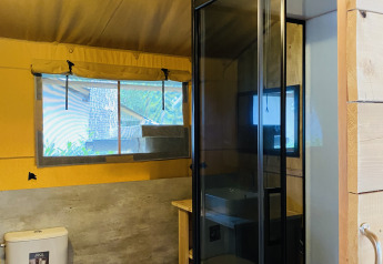 Bathroom inside a safari tent with toilet, shower, and window at Familiepark Goolderheide, Belgium.