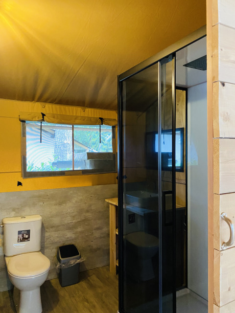 Badezimmer in einem Safari-Zelt mit Toilette, Dusche und Fenster im Familiepark Goolderheide, Belgien.