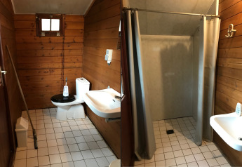 Bagno di una tenda safari al Familiepark Goolderheide, Belgio, con wc, lavandino e doccia separata.