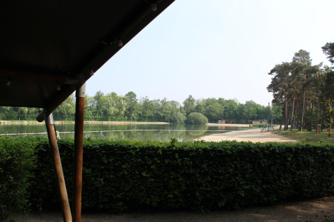 Vista dalla tenda safari con servizi igienici al Familiepark Goolderheide, Belgio, su lago e alberi.
