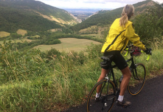 Cyklist iført gul jakke nyder den smukke udsigt over bakkerne ved Camping Le Gallo Romain, Auvergne-Rhône-Alpes.