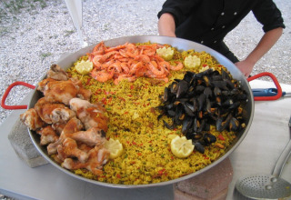 En stor pande med paella med kylling, rejer og muslinger på Camping Le Gallo Romain i Auvergne-Rhône-Alpes.