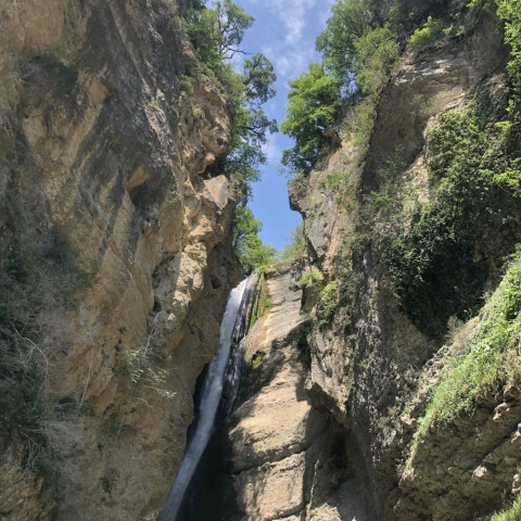 Cascada entre altos acantilados y vegetación en Camping Le Gallo Romain, Auvergne-Rhône-Alpes, Francia.