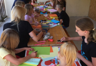 Bambini e adulti partecipano a un laboratorio creativo al Camping Le Gallo Romain, Auvergne-Rhône-Alpes, Francia.