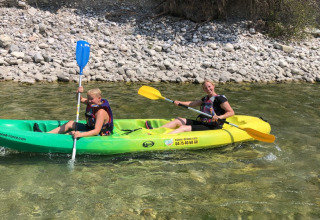 Due persone remano in un kayak verde e giallo su un fiume limpido al Camping Le Gallo Romain, Francia.