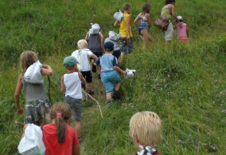Un gruppo di bambini sale una collina verde con un adulto al Camping Le Gallo Romain, Auvergne-Rhône-Alpes.