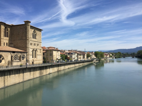Vista del río cerca de Barbières, Auvernia-Ródano-Alpes, Francia, con edificaciones históricas y cielo azul.