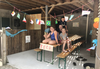 Børn leger ved Kids Club-området med dekorationer og flag på Camping Le Gallo Romain, Auvergne-Rhône-Alpes.