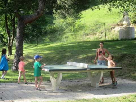 Niños y adultos juegan al tenis de mesa exterior en Camping Le Gallo Romain, Auvergne-Rhône-Alpes, Francia.