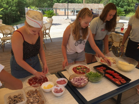 Adolescentes preparando pizzas al aire libre en Camping Le Gallo Romain, Auvergne-Rhône-Alpes, Francia.