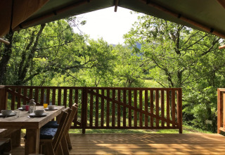 Udsigt fra en træterrasse med bord og stole på Camping Le Gallo Romain i Auvergne-Rhône-Alpes, Frankrig.