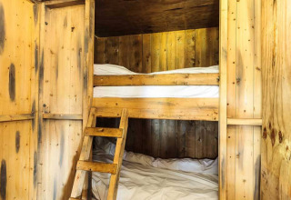 Binnenzicht van een glampingaccommodatie met houten stapelbedden en warme, sfeervolle houten panelen.