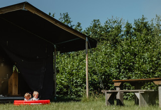Due bambini giocano in una piccola piscina davanti a una tenda presso Feather Down De Zeekraal Terschelling, Frisia, Paesi Bassi.