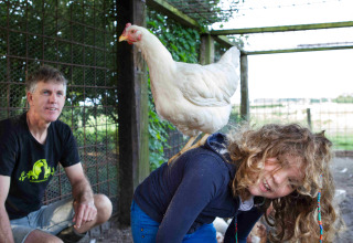 Mann und Kind im Ferienpark in Friesland, Niederlande, mit einem weißen Huhn auf dem Rücken des Kindes.