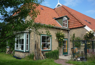 Charmerende murstenshus med rødt tegltag og have, set i Feather Down De Zeekraal Terschelling, Friesland.