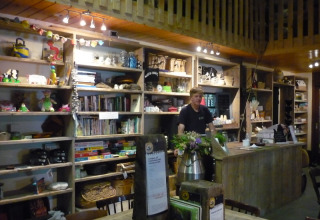 Indretning af Feather Down De Zeekraal Terschelling feriepark med træmøbler, bøger og en receptionsdisk.