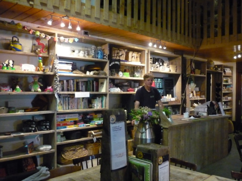 Indretning af Feather Down De Zeekraal Terschelling feriepark med træmøbler, bøger og en receptionsdisk.