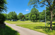 Campingvogne parkeret under træer på en solrig dag ved Camp Diekirch feriepark i Diekirch, Luxembourg.
