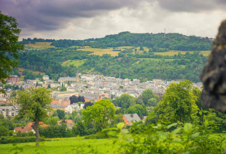 Vista panoramica su Diekirch, Lussemburgo, circondata da colline verdi e natura rigogliosa sotto nubi grigie.