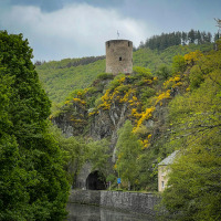 Una torre di pietra rotonda si erge su una collina boscosa vicino a Diekirch, Lussemburgo, con un tunnel sotto.