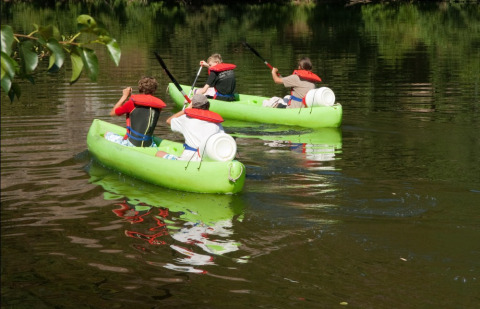 Dos canoas verdes con cuatro personas remando en un lago en Camping lac Aux Oiseaux, Occitania, Francia.