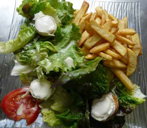 Plato con papas fritas, ensalada verde, rodaja de tomate y queso de cabra en Camping lac Aux Oiseaux, Occitanie.