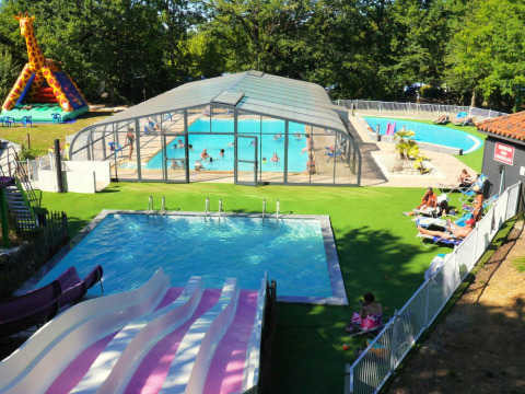 Vista aérea de piscinas, toboganes y jirafa inflable en Camping lac Aux Oiseaux, Occitania, Francia.